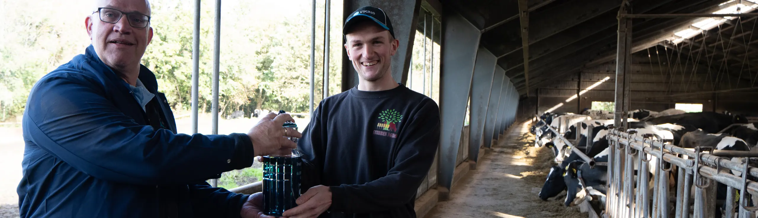 Ydelsestekniker Harmen Scholten Overrækker Gave Fra IDEXX – En Unikt Fremstillet Mælkejunge I Glas